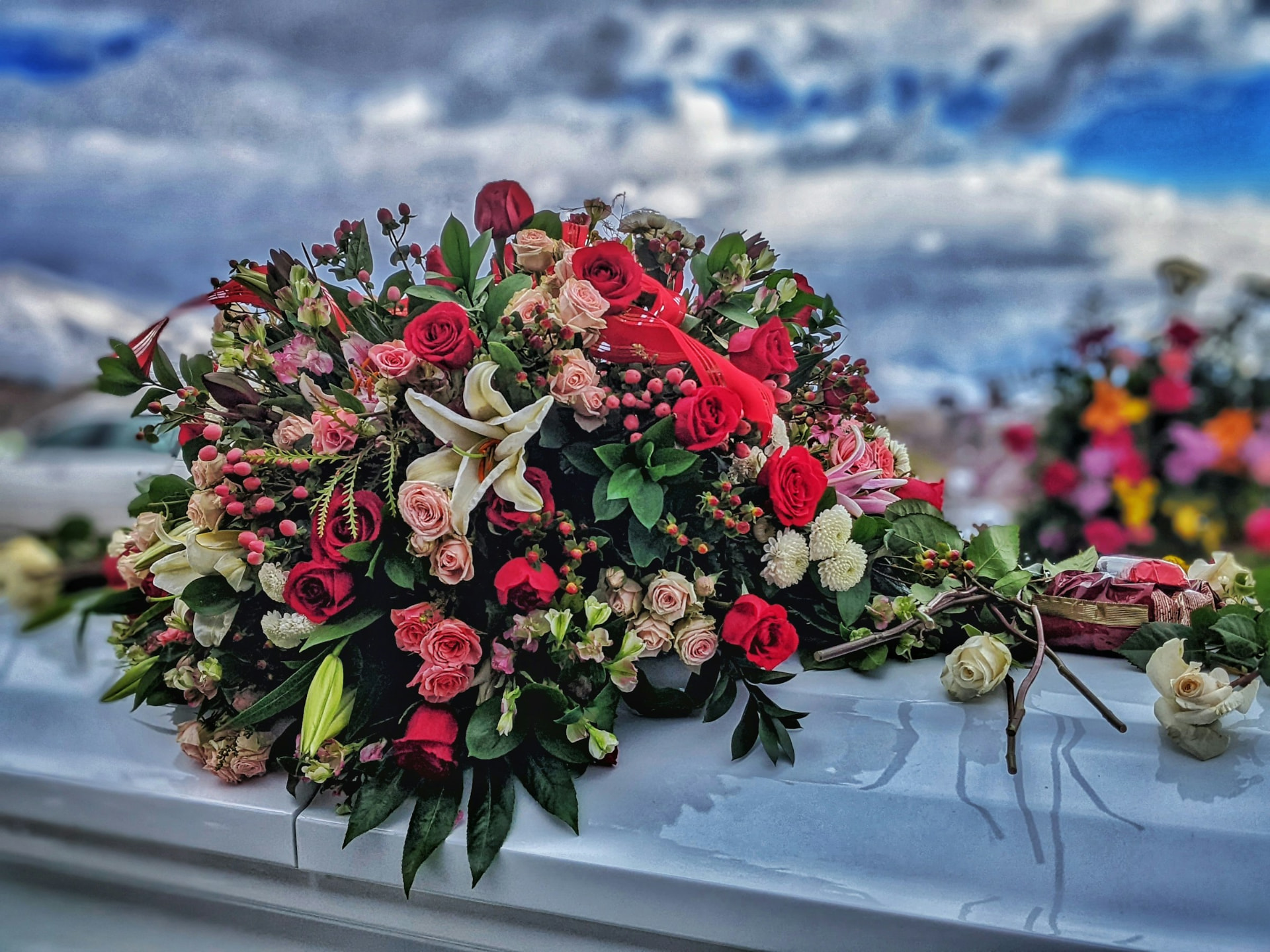 Red, blush, and cream funeral flowers arranged with abundant greenery
